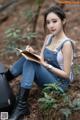 A woman sitting on the ground writing in a notebook.