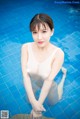 A woman in a white bathing suit sitting in a pool.