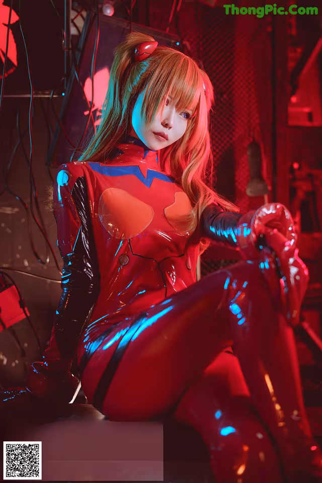 A woman in a red latex outfit sitting on a stage.