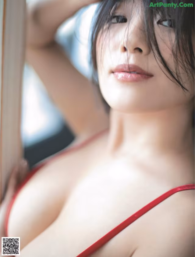 A woman in a red lingerie leaning against a window.