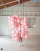 A woman standing in front of a bunch of pink balloons.