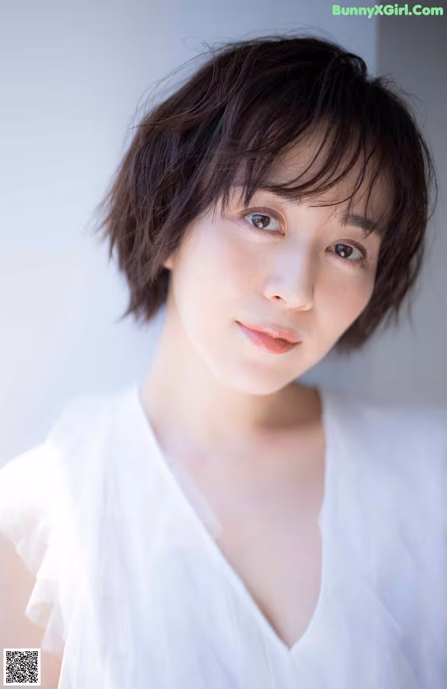 A woman in a white shirt is posing for a picture.