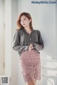 a woman in a gray sweater and pink skirt posing for a picture