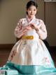 A woman in a pink and blue hanbok is posing for a picture.