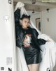 A woman in a black leather jacket and skirt posing for a magazine.