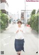 A woman walking down a street holding a bag.