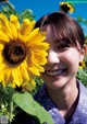 A young girl smiles as she stands in a field of sunflowers.