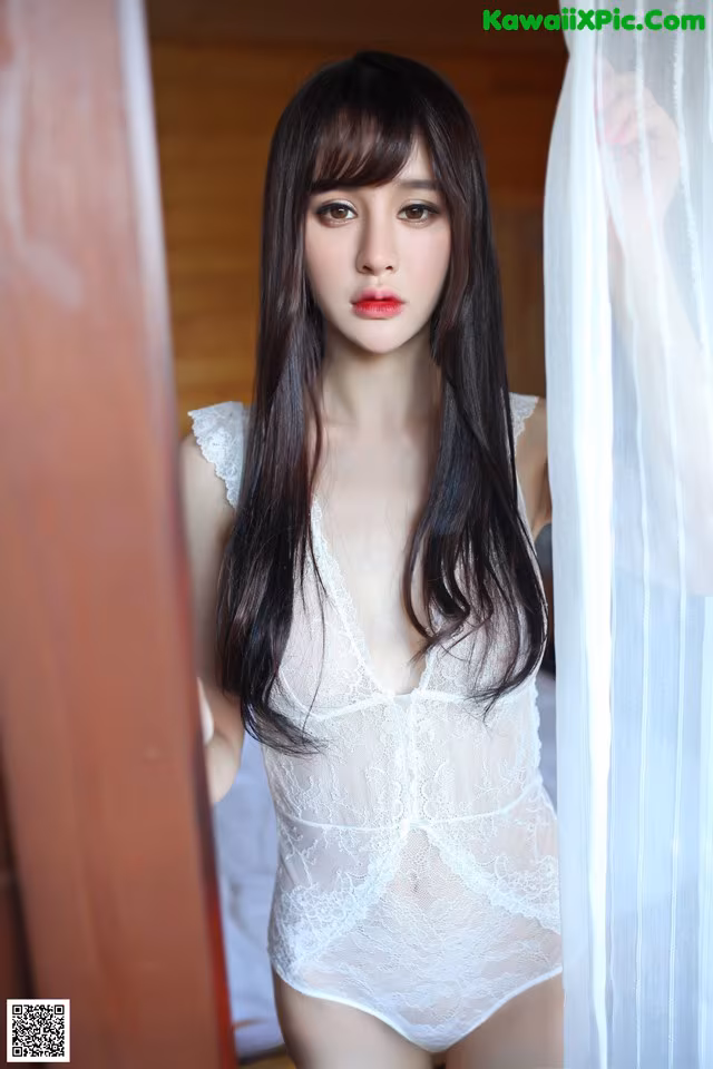 A woman in a white lingerie standing in front of a window.