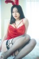 A woman in a red lingerie sitting on a bed.