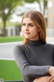 A woman in a black turtle neck top leaning against a railing.