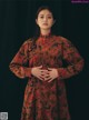 A woman in a red floral dress poses for a picture.