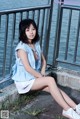 A woman sitting on the edge of a pier next to the water.