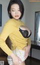 A woman in a yellow sweater and black bra posing for the camera.