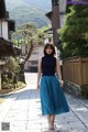 A woman in a blue skirt is walking down a street.