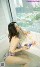 A woman in a bathing suit sitting in a bathtub.