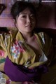 A woman in a kimono laying on a bed.