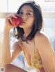 A woman in lingerie holding an apple in her hand.