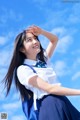 A woman in a school uniform with a blue backpack.