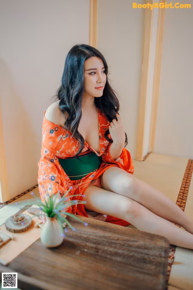 A woman in a red kimono sitting on a wooden table.